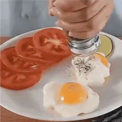 Œufs pochés et tomates en tranches dans une assiette avec un assaisonnement saupoudré à la main.